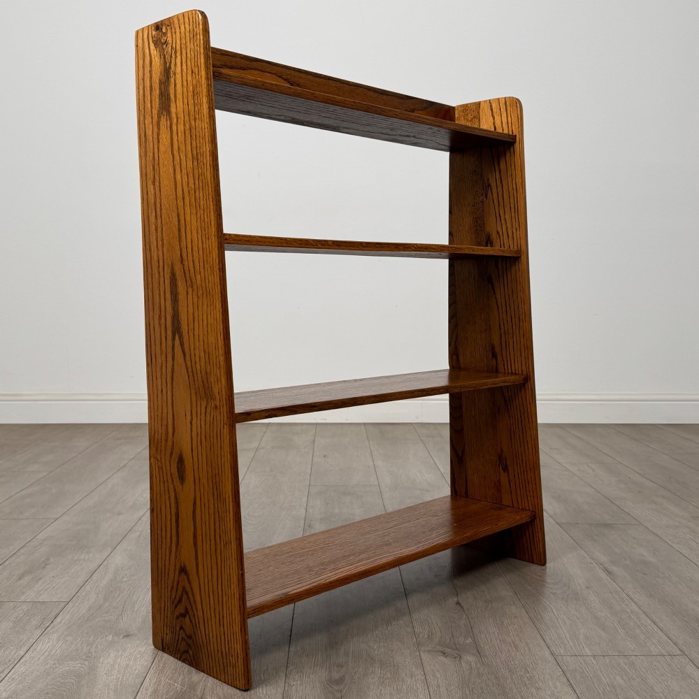 An open golden oak bookcase featuring four horizontal shelves arranged vertically with solid side panels. View IX