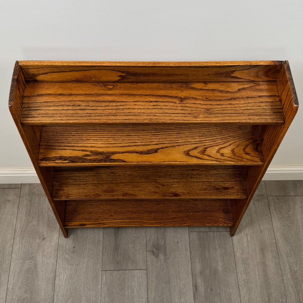 An open golden oak bookcase featuring four horizontal shelves arranged vertically with solid side panels. View X