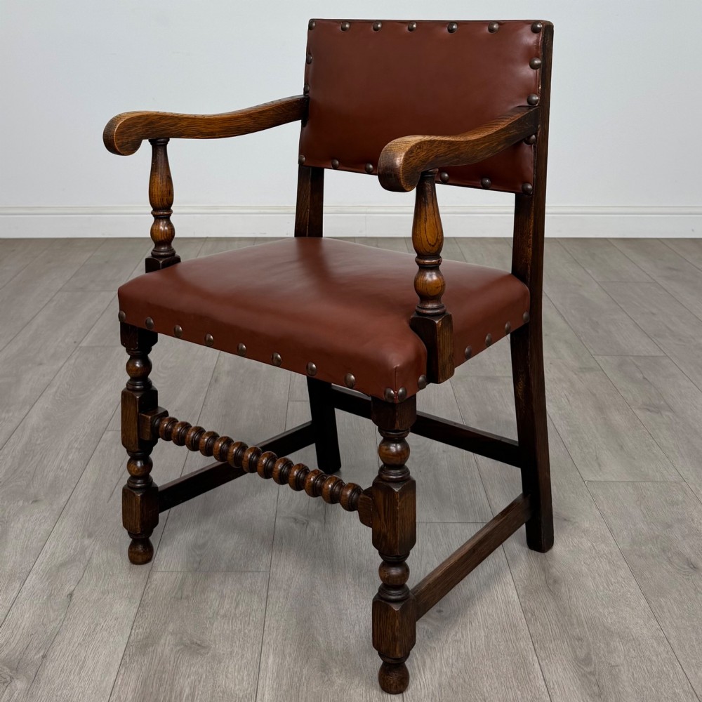 A set of eight dark oak dining chairs featuring brown leather upholstery secured with brass studding, turned legs, and including two armchairs. View II
