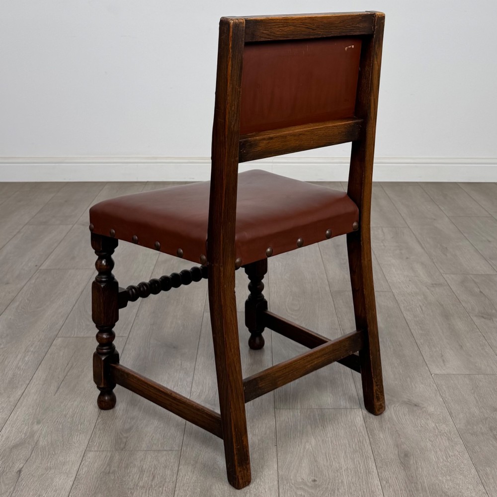 A set of eight dark oak dining chairs featuring brown leather upholstery secured with brass studding, turned legs, and including two armchairs. View IV