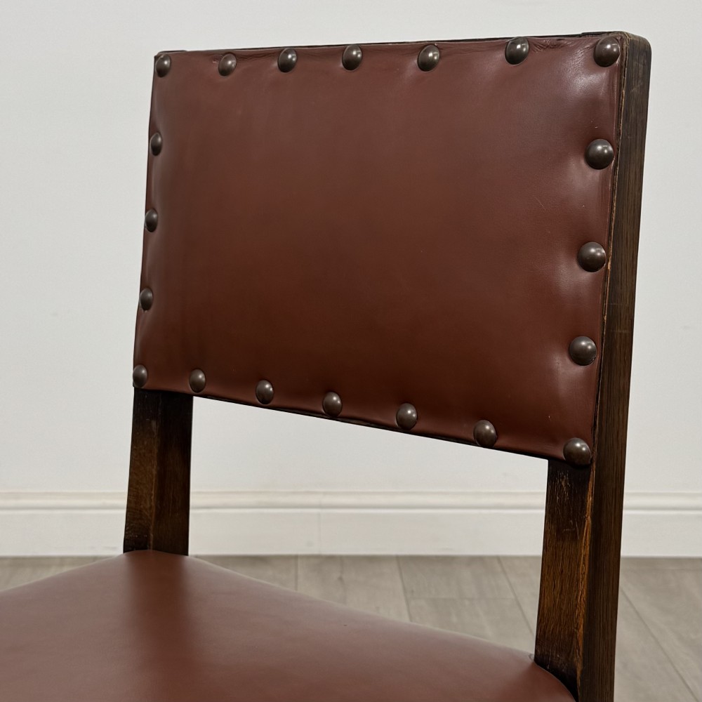 A set of eight dark oak dining chairs featuring brown leather upholstery secured with brass studding, turned legs, and including two armchairs. View V