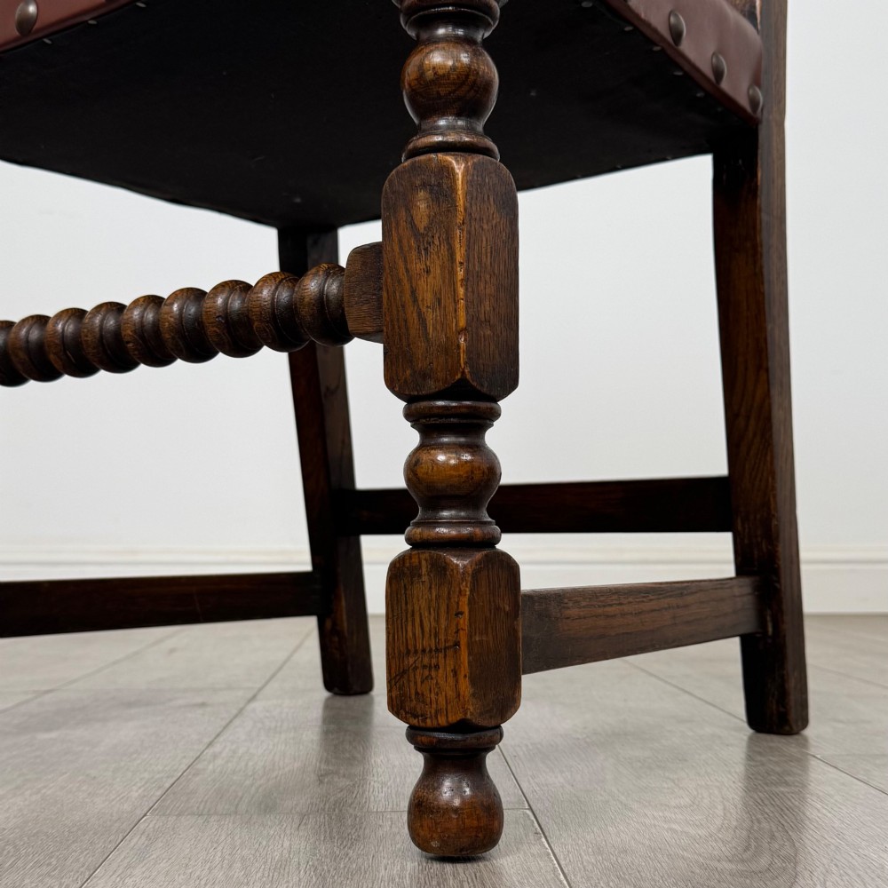 A set of eight dark oak dining chairs featuring brown leather upholstery secured with brass studding, turned legs, and including two armchairs. View VII