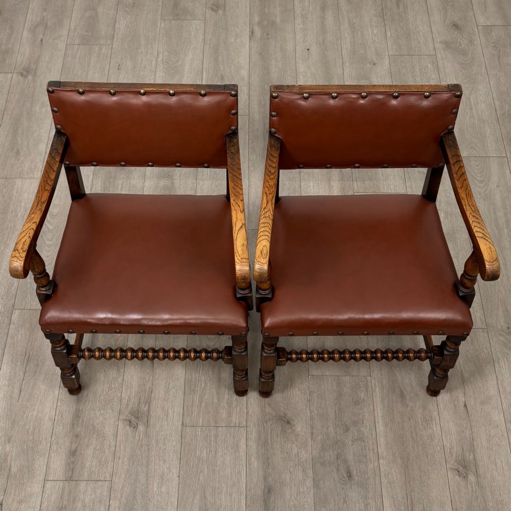A set of eight dark oak dining chairs featuring brown leather upholstery secured with brass studding, turned legs, and including two armchairs. View VIII