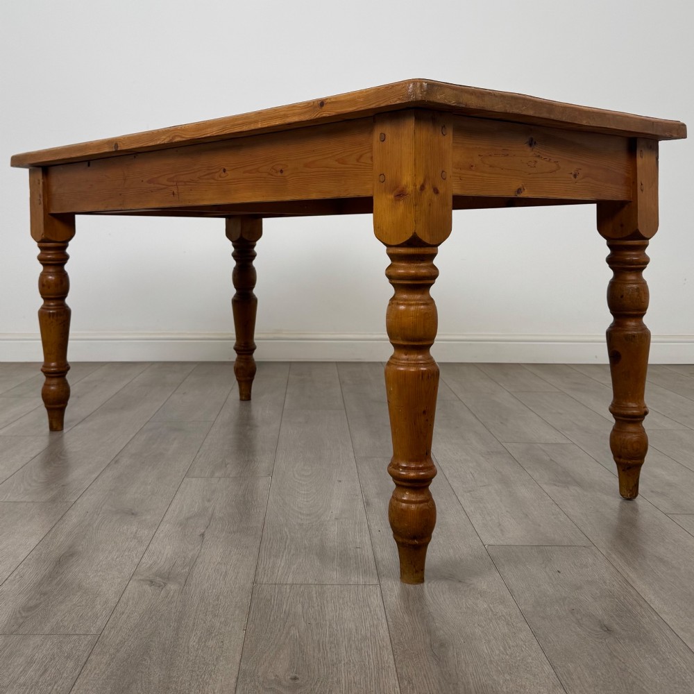 A solid pine farmhouse dining table featuring four turned legs and a single side frieze drawer with a wooden knob handle. View III