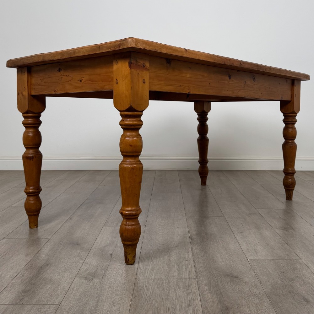 A solid pine farmhouse dining table featuring four turned legs and a single side frieze drawer with a wooden knob handle. View V