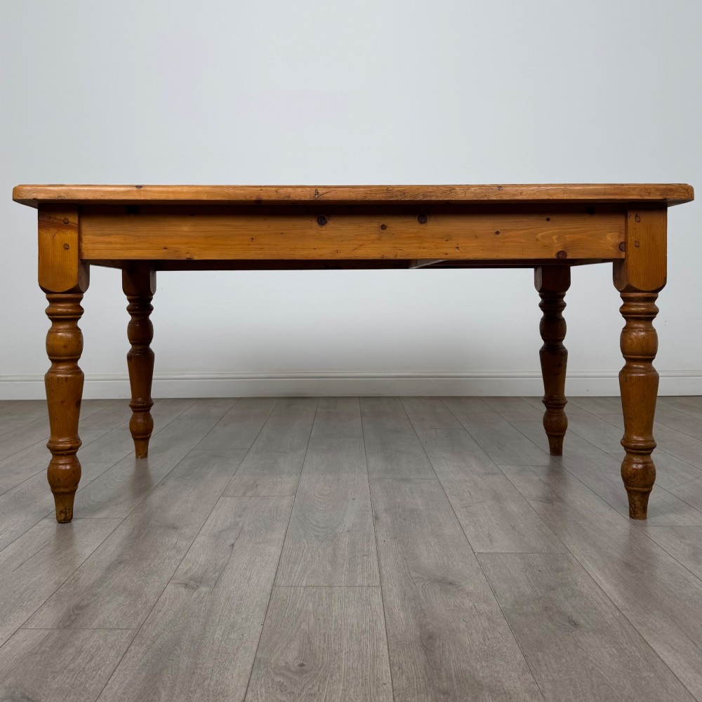 A solid pine farmhouse dining table featuring four turned legs and a single side frieze drawer with a wooden knob handle. View VI