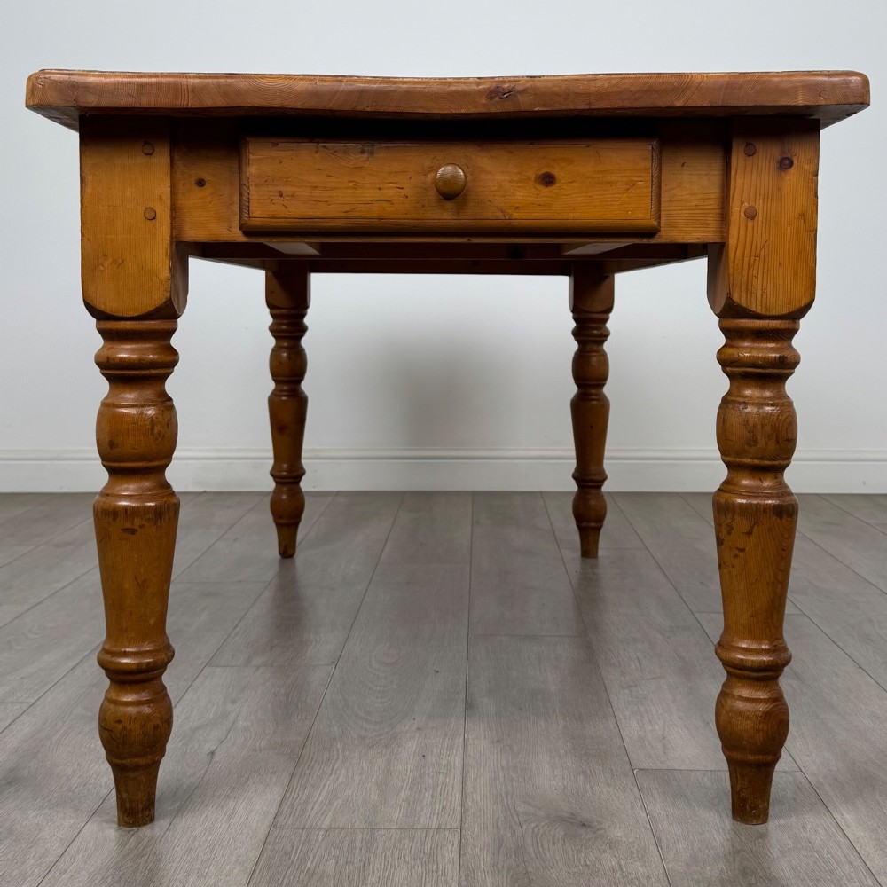 A solid pine farmhouse dining table featuring four turned legs and a single side frieze drawer with a wooden knob handle. View VIII