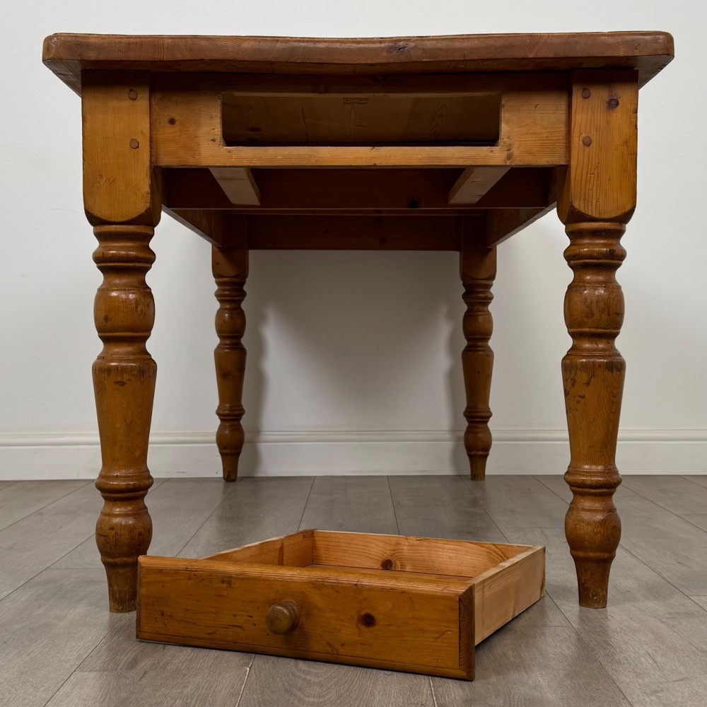 A solid pine farmhouse dining table featuring four turned legs and a single side frieze drawer with a wooden knob handle. View IX