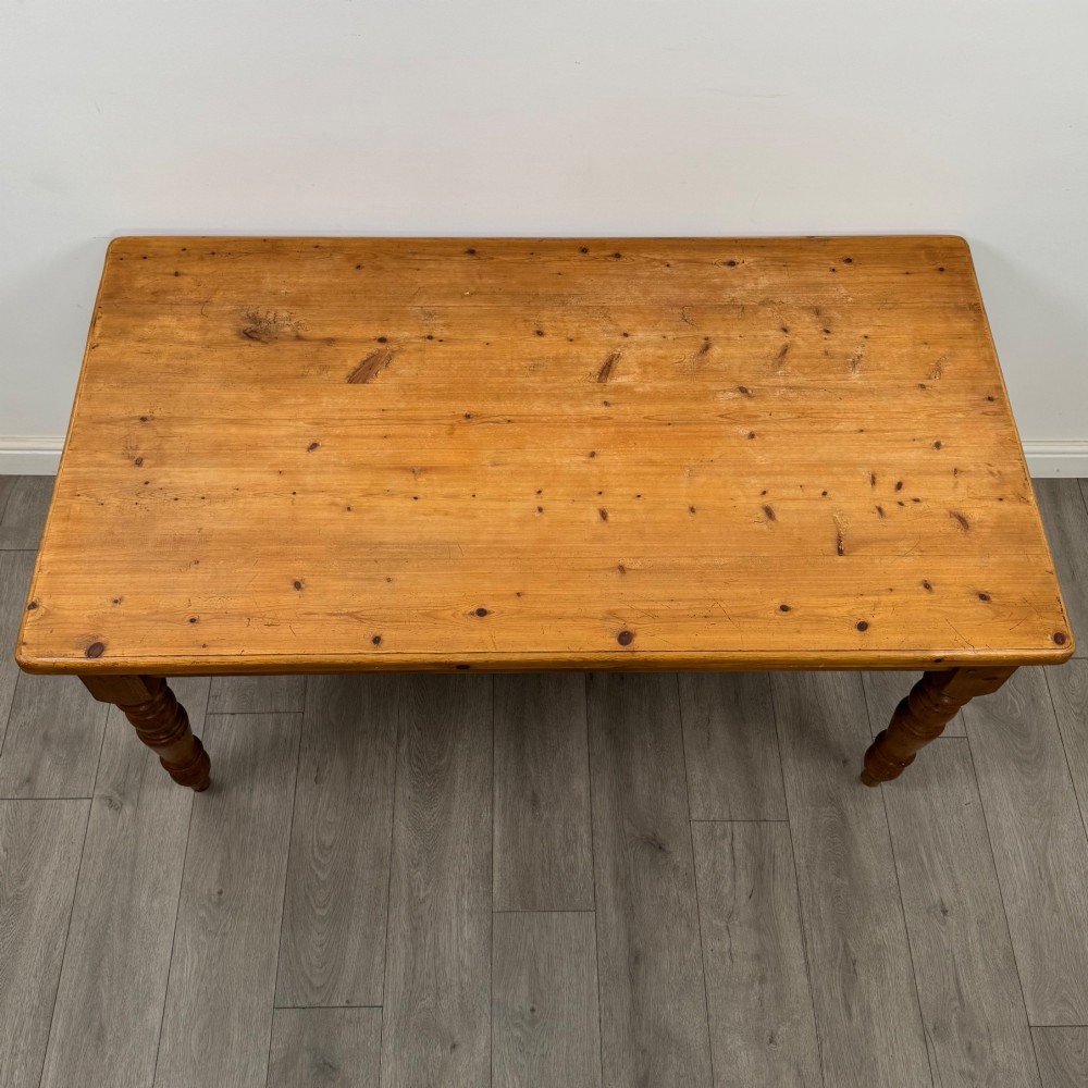 A solid pine farmhouse dining table featuring four turned legs and a single side frieze drawer with a wooden knob handle. View XI