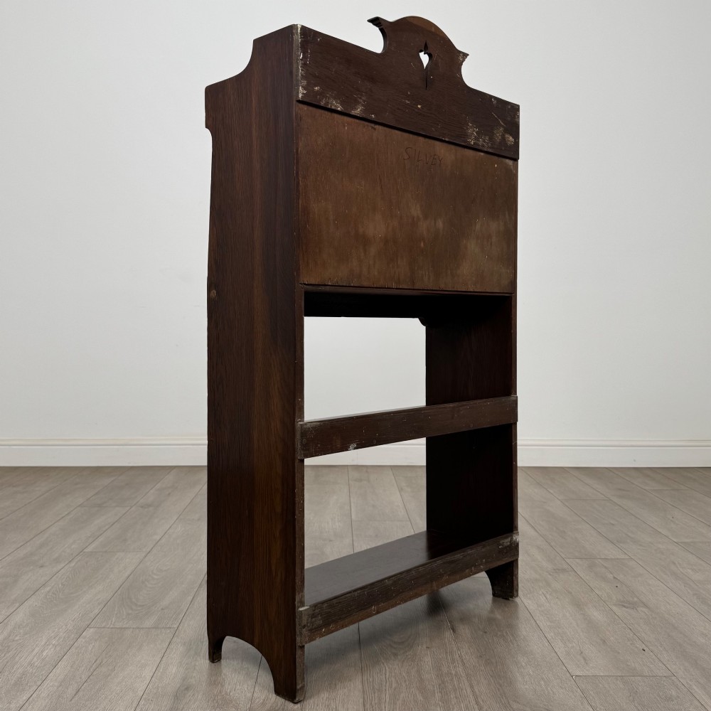 A dark mahogany Art Nouveau style bureau featuring a drop-front writing flap with elongated metal strap hinges above two open shelves. View VI