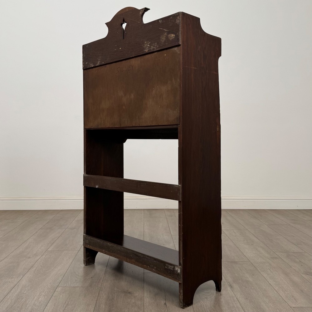A dark mahogany Art Nouveau style bureau featuring a drop-front writing flap with elongated metal strap hinges above two open shelves. View VIII