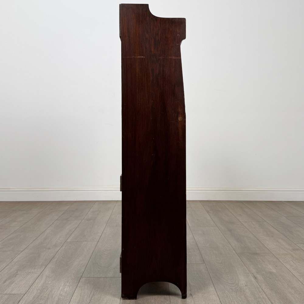 A dark mahogany Art Nouveau style bureau featuring a drop-front writing flap with elongated metal strap hinges above two open shelves. View IX