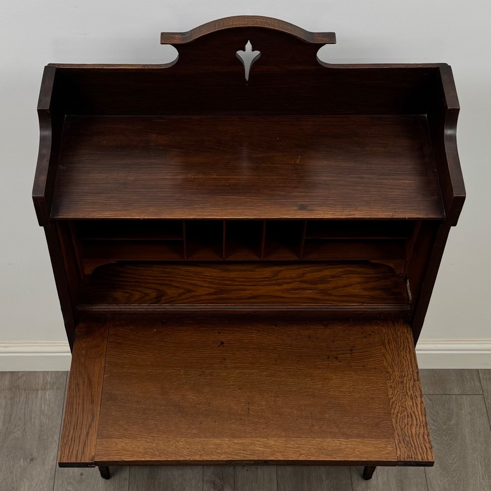 A dark mahogany Art Nouveau style bureau featuring a drop-front writing flap with elongated metal strap hinges above two open shelves. View XII