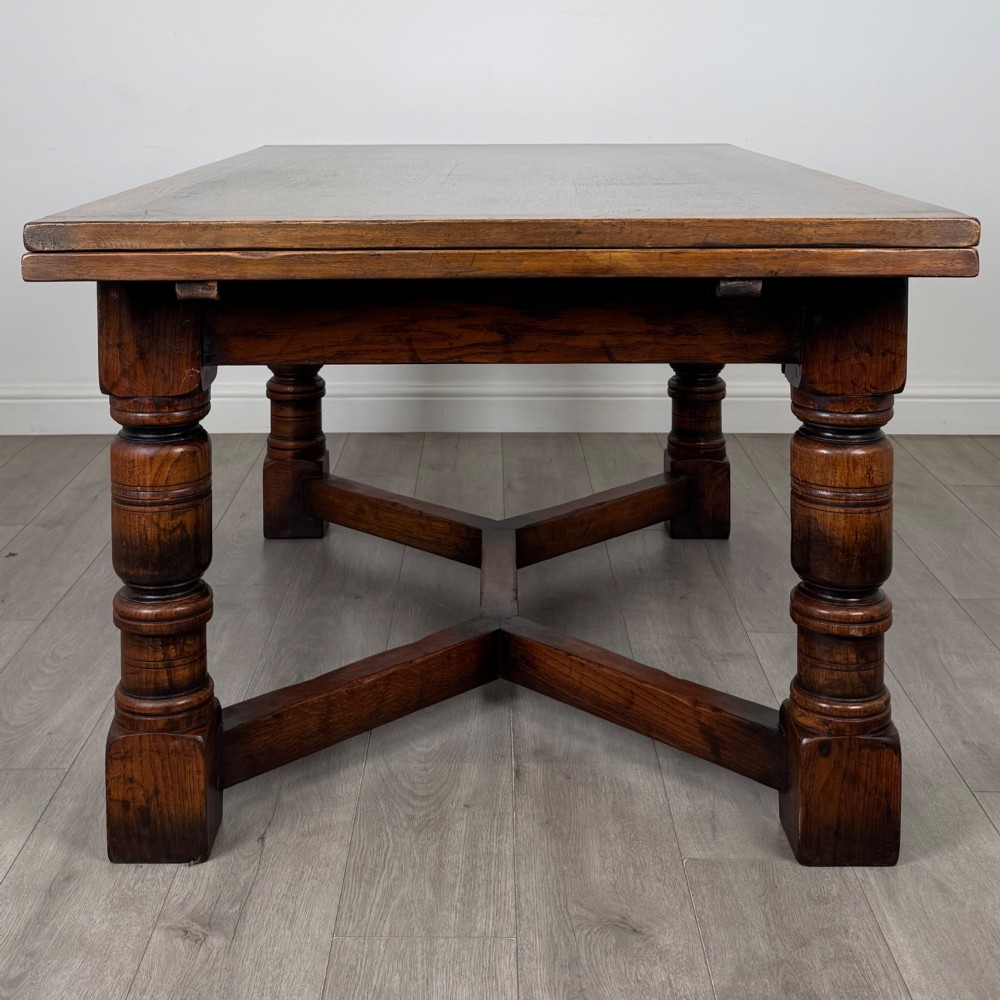 An antique oak dining table surrounded by six matching brown leather upholstered chairs with brass stud details. View IV