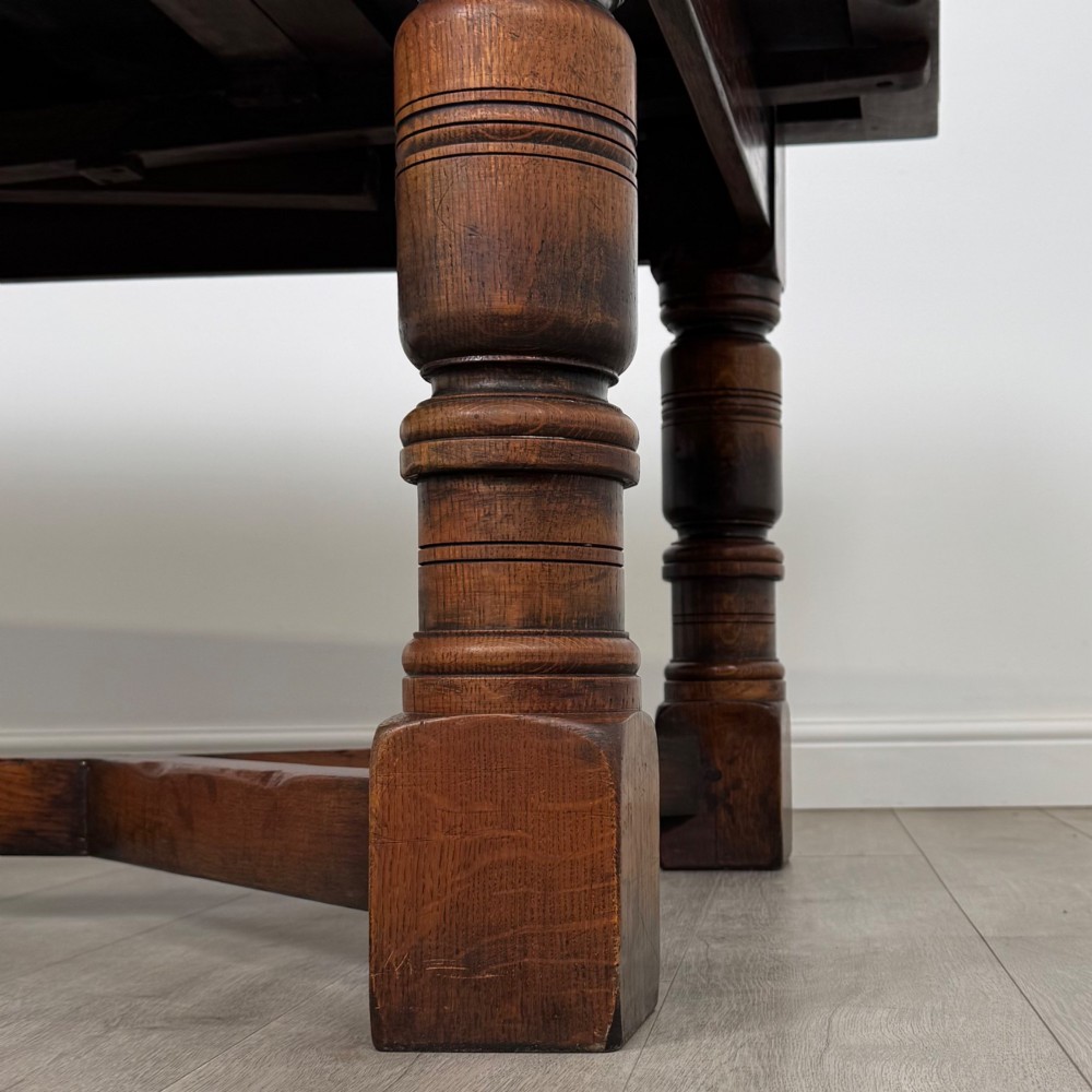 An antique oak dining table surrounded by six matching brown leather upholstered chairs with brass stud details. View VII