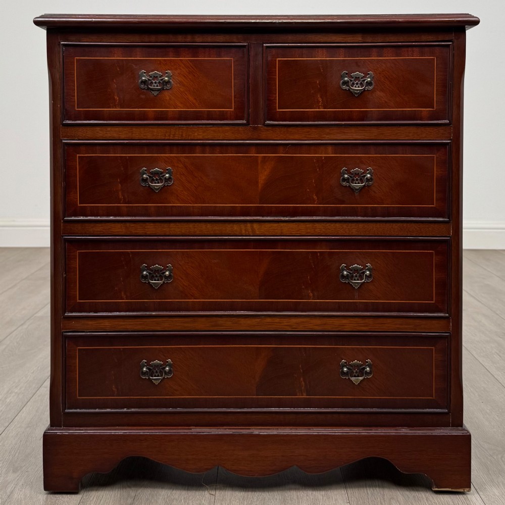 A 20th-century inlaid mahogany chest of drawers featuring two short over three long drawers with decorative brass handles.