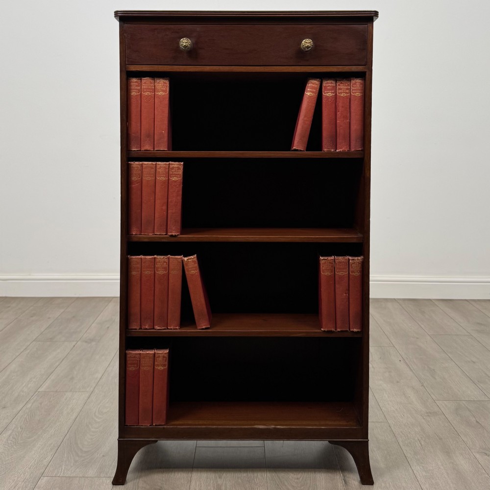 A tall 19th-century Regency mahogany open bookcase featuring four open shelves, a top drawer with twin brass knobs, and flared feet.