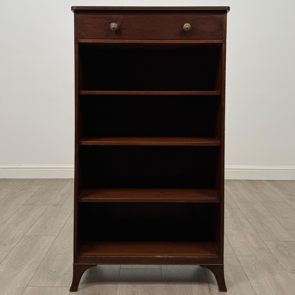 A tall 19th-century Regency mahogany open bookcase featuring four open shelves, a top drawer with twin brass knobs, and flared feet. View II