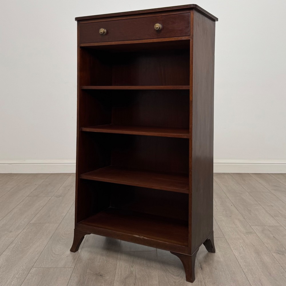 A tall 19th-century Regency mahogany open bookcase featuring four open shelves, a top drawer with twin brass knobs, and flared feet. View III