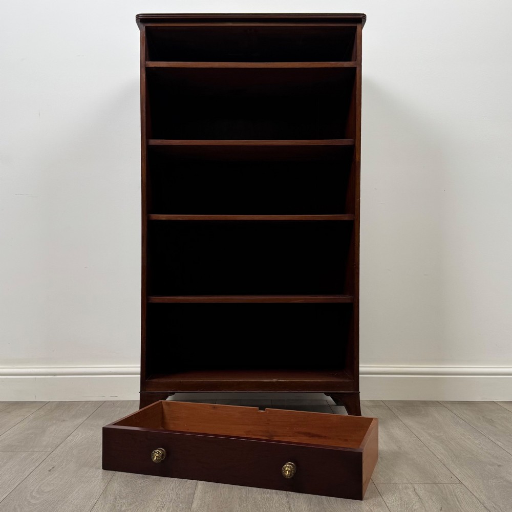 A tall 19th-century Regency mahogany open bookcase featuring four open shelves, a top drawer with twin brass knobs, and flared feet. View XI