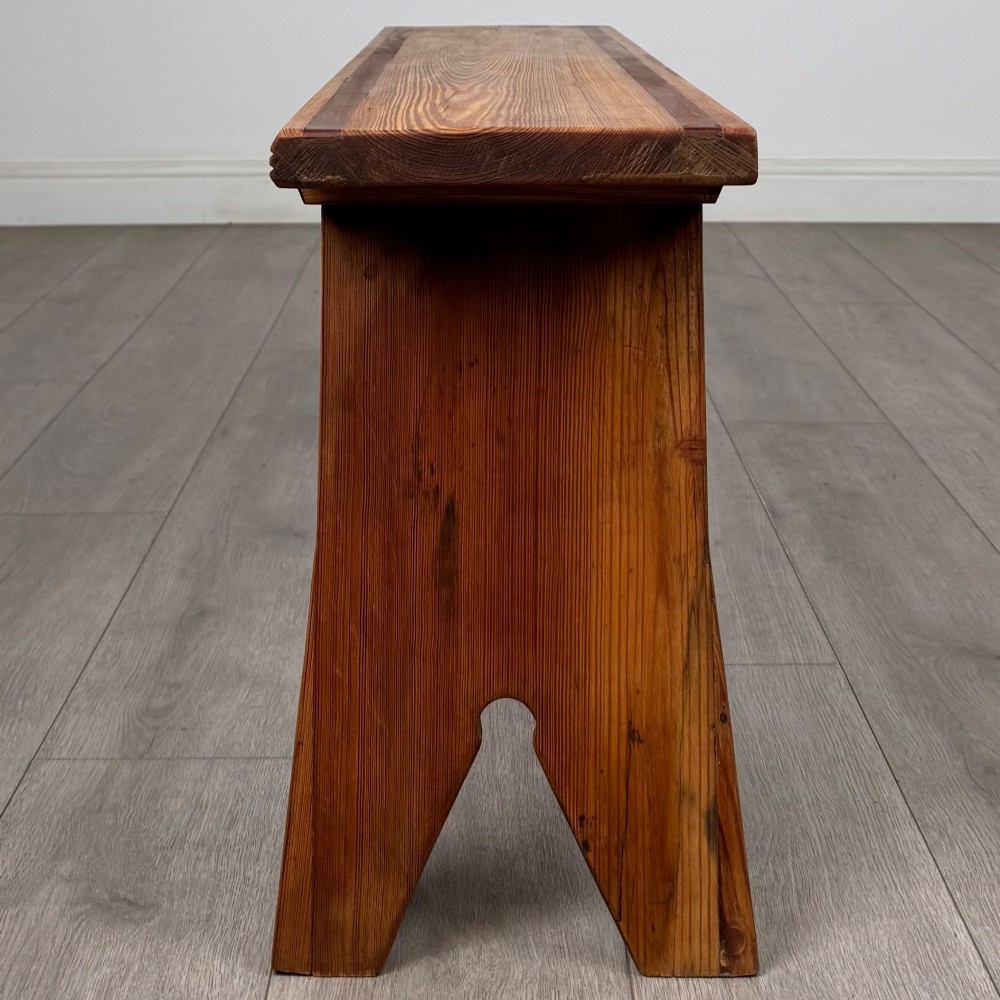 A pitch pine wooden bench with angled trestle legs, diagonal side braces, and a reeded edge along the top rectangular seat. View II