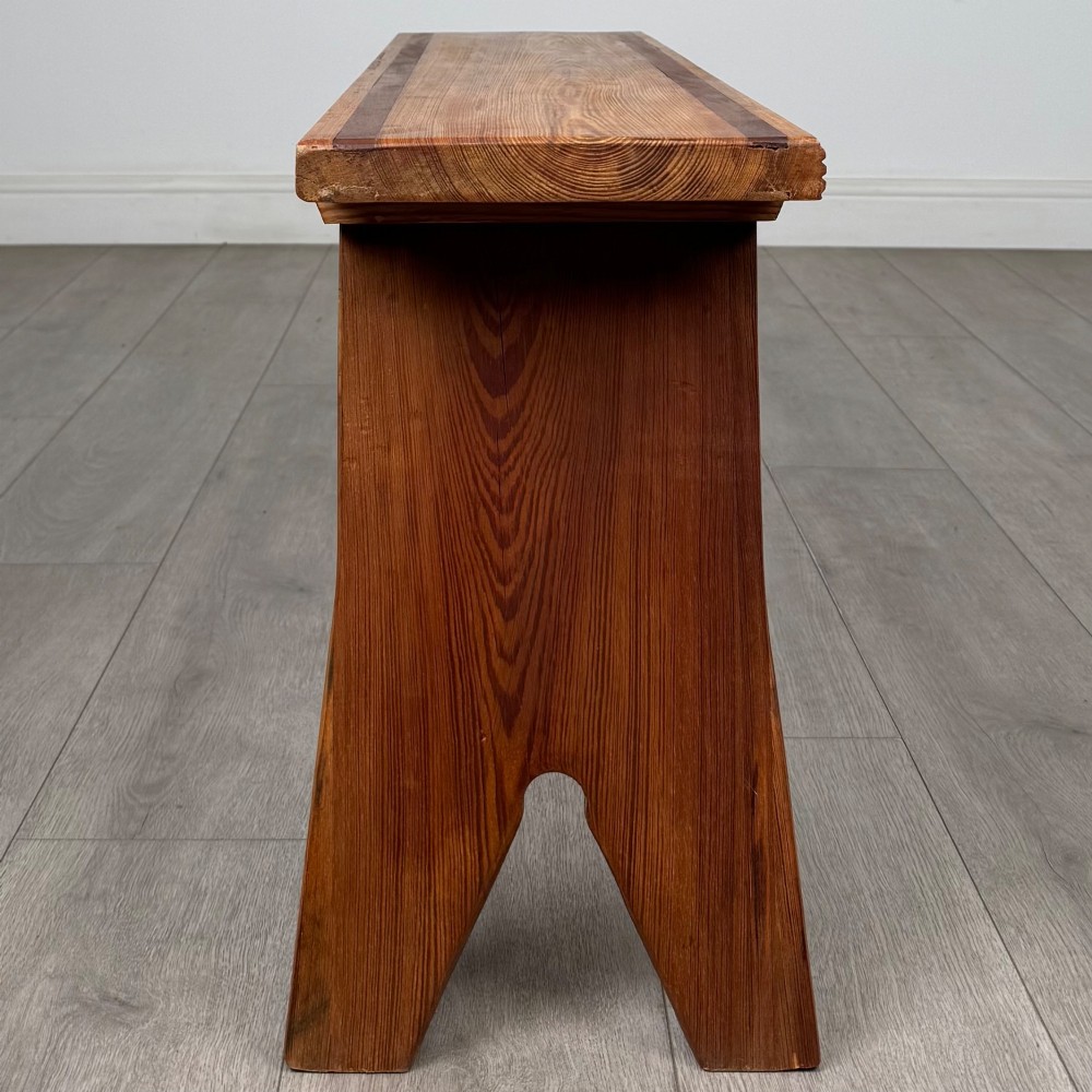 A pitch pine wooden bench with angled trestle legs, diagonal side braces, and a reeded edge along the top rectangular seat. View VI