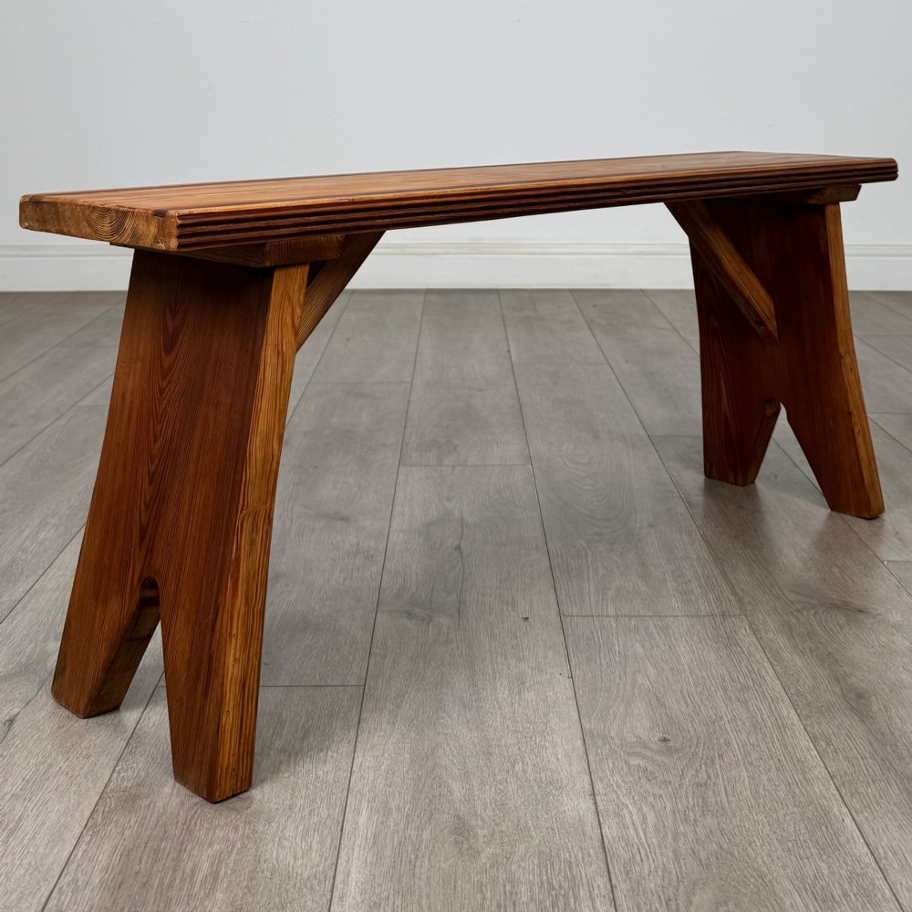 A pitch pine wooden bench with angled trestle legs, diagonal side braces, and a reeded edge along the top rectangular seat. View VII