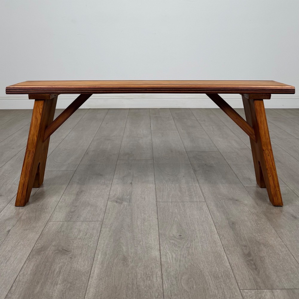 A pitch pine wooden bench with angled trestle legs, diagonal side braces, and a reeded edge along the top rectangular seat. View VIII