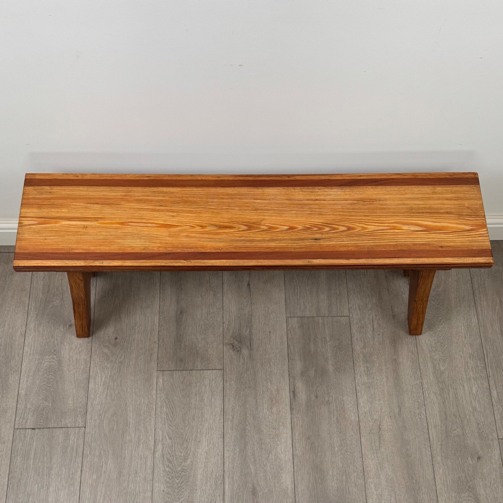 A pitch pine wooden bench with angled trestle legs, diagonal side braces, and a reeded edge along the top rectangular seat. View IX