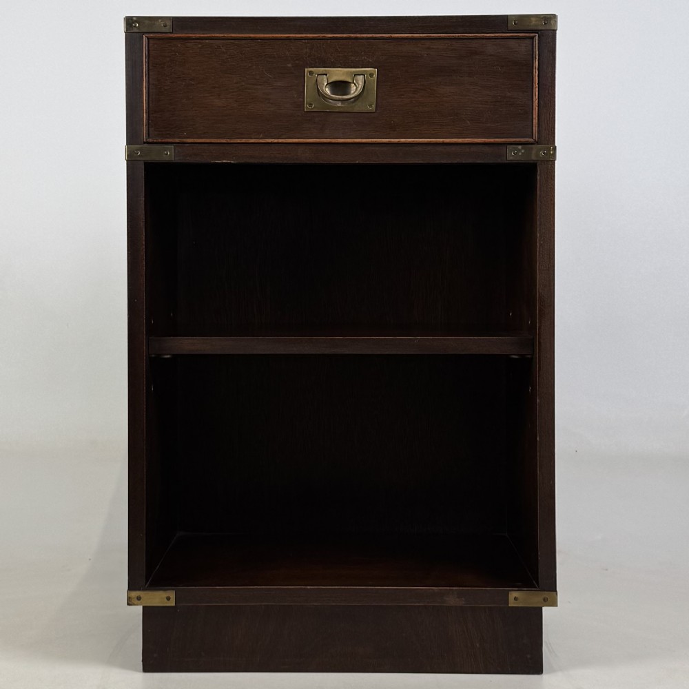 A dark mahogany campaign style cabinet featuring a single upper drawer with a flush brass handle, brass corner mounts, and two open lower shelves. View II