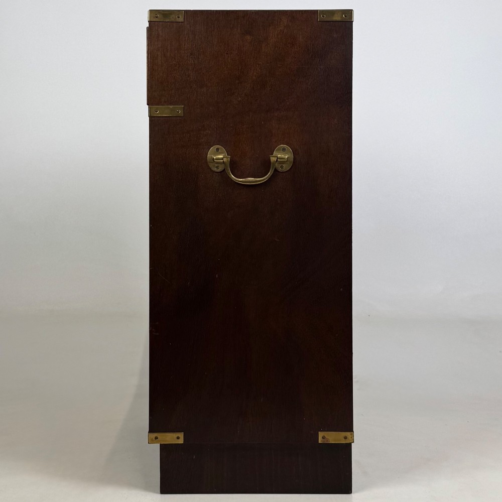 A dark mahogany campaign style cabinet featuring a single upper drawer with a flush brass handle, brass corner mounts, and two open lower shelves. View IV