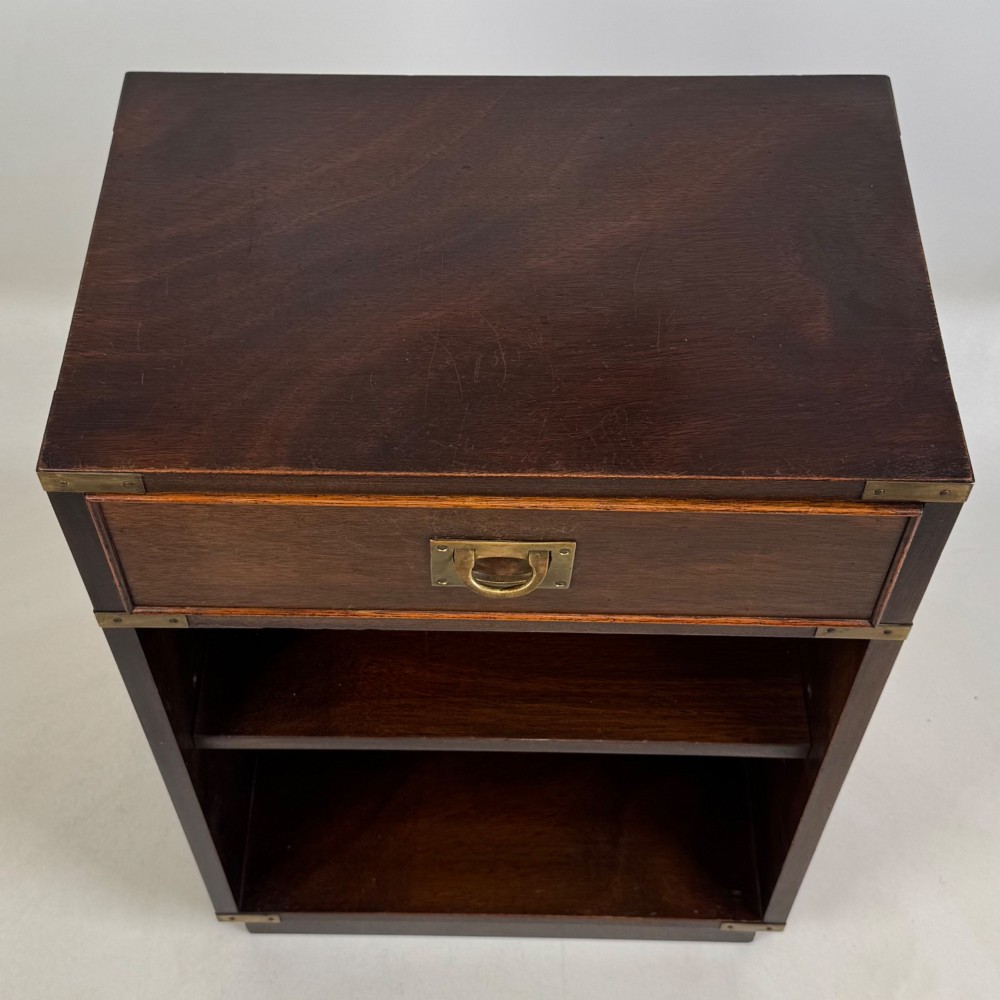 A dark mahogany campaign style cabinet featuring a single upper drawer with a flush brass handle, brass corner mounts, and two open lower shelves. View XII