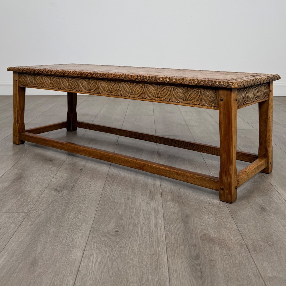A low rectangular golden oak coffee table featuring carved leaf patterns along the apron and edges, supported by straight legs with a lower stretcher frame. View II
