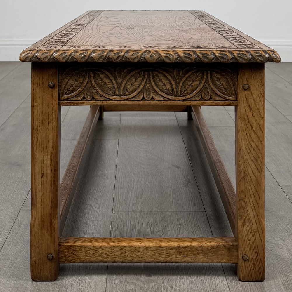 A low rectangular golden oak coffee table featuring carved leaf patterns along the apron and edges, supported by straight legs with a lower stretcher frame. View III
