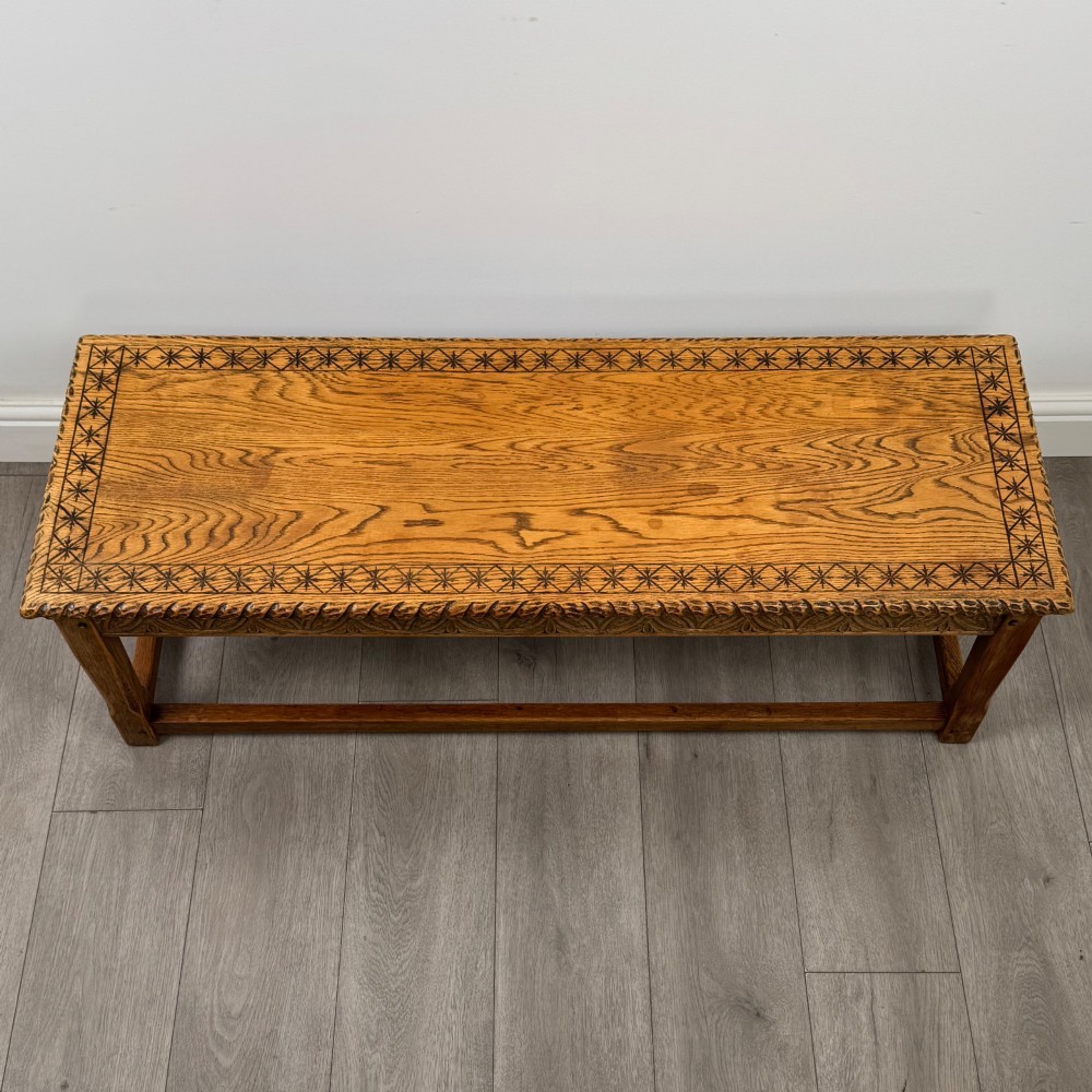 A low rectangular golden oak coffee table featuring carved leaf patterns along the apron and edges, supported by straight legs with a lower stretcher frame. View IX