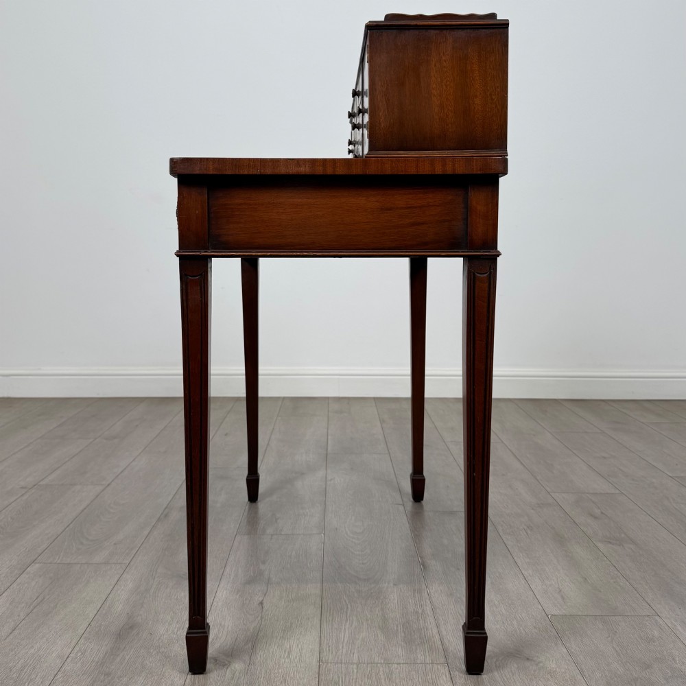 A mahogany writing table featuring a raised superstructure with small drawers and side cupboards above two main frieze drawers, supported by square tapered fluted legs. View III