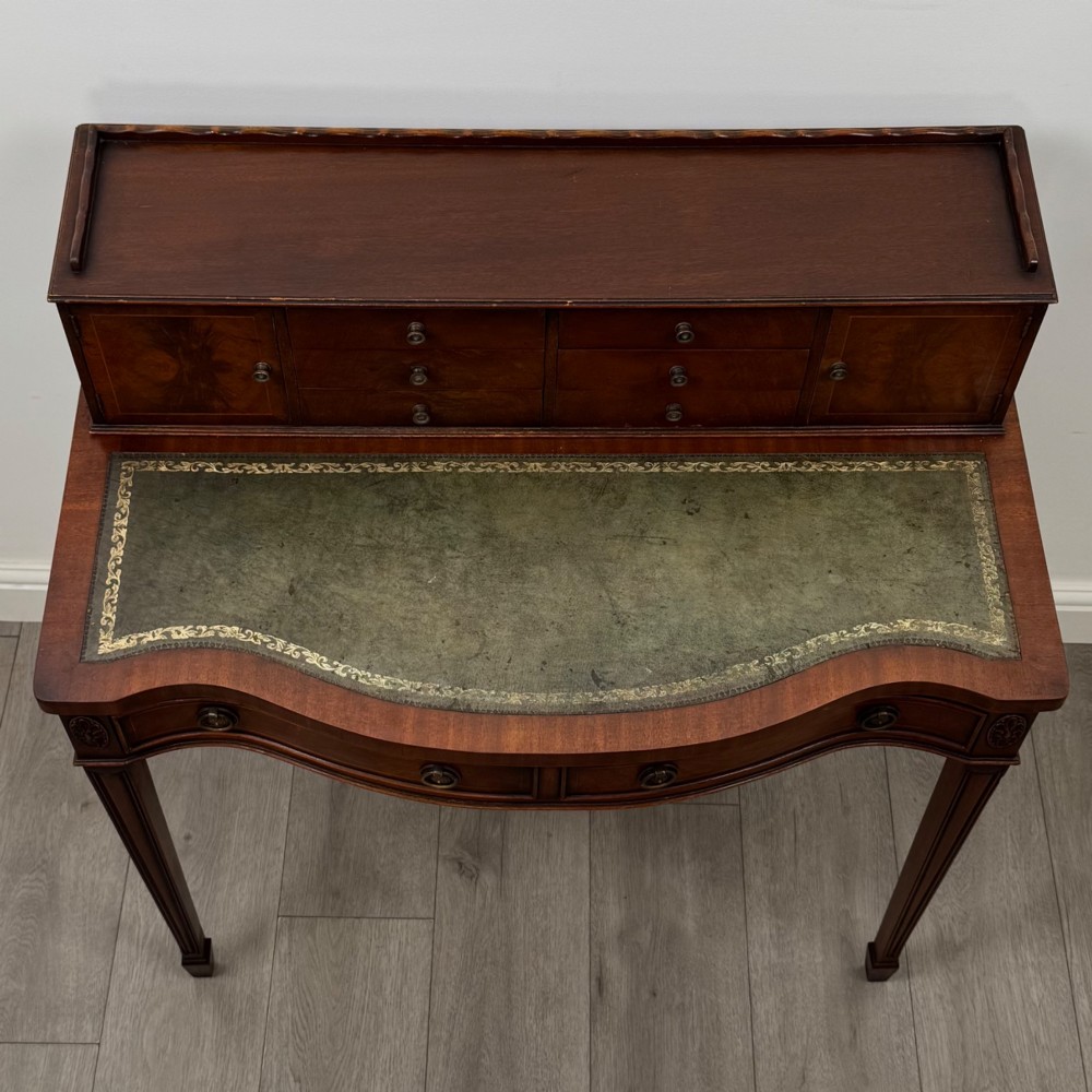 A mahogany writing table featuring a raised superstructure with small drawers and side cupboards above two main frieze drawers, supported by square tapered fluted legs. View IX