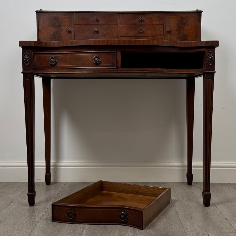 A mahogany writing table featuring a raised superstructure with small drawers and side cupboards above two main frieze drawers, supported by square tapered fluted legs. View X