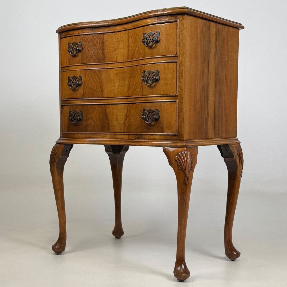 A small 20th-century walnut chest featuring three drawers, brass handles, and tall carved cabriole legs. View II