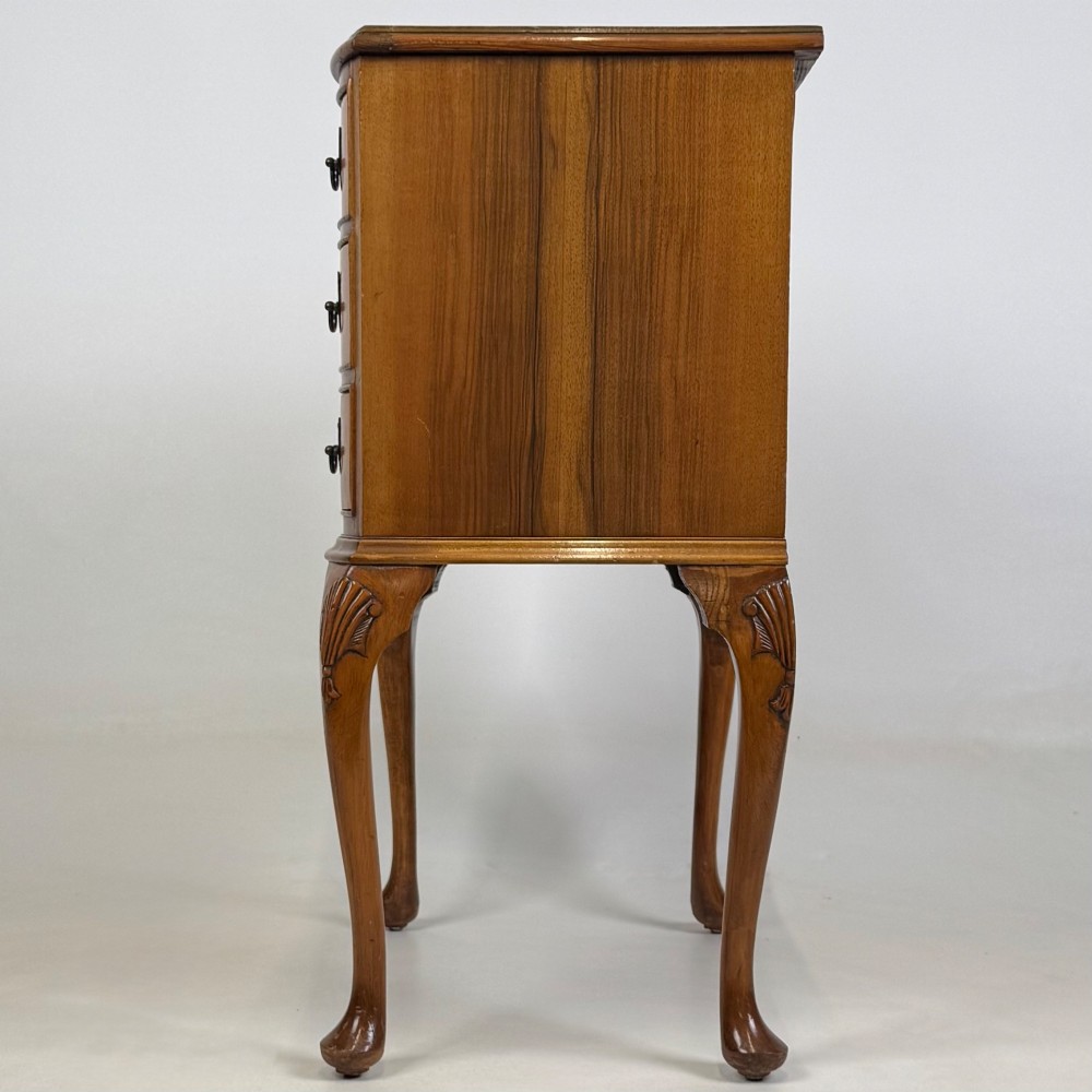 A small 20th-century walnut chest featuring three drawers, brass handles, and tall carved cabriole legs. View III