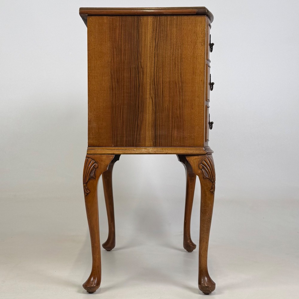 A small 20th-century walnut chest featuring three drawers, brass handles, and tall carved cabriole legs. View VII