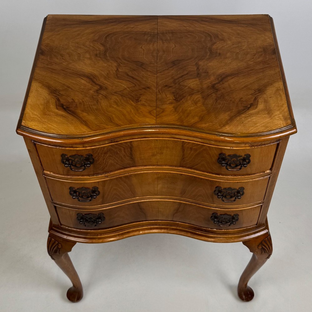 A small 20th-century walnut chest featuring three drawers, brass handles, and tall carved cabriole legs. View IX