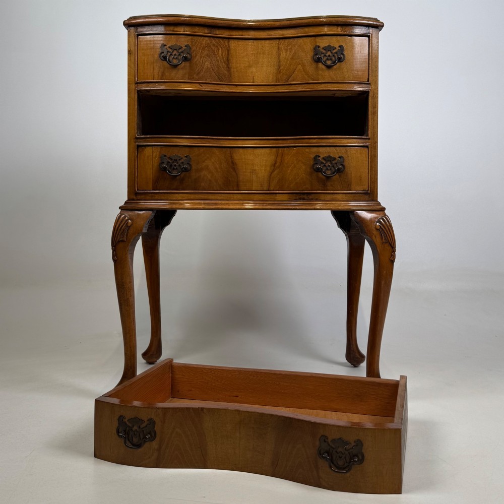 A small 20th-century walnut chest featuring three drawers, brass handles, and tall carved cabriole legs. View X