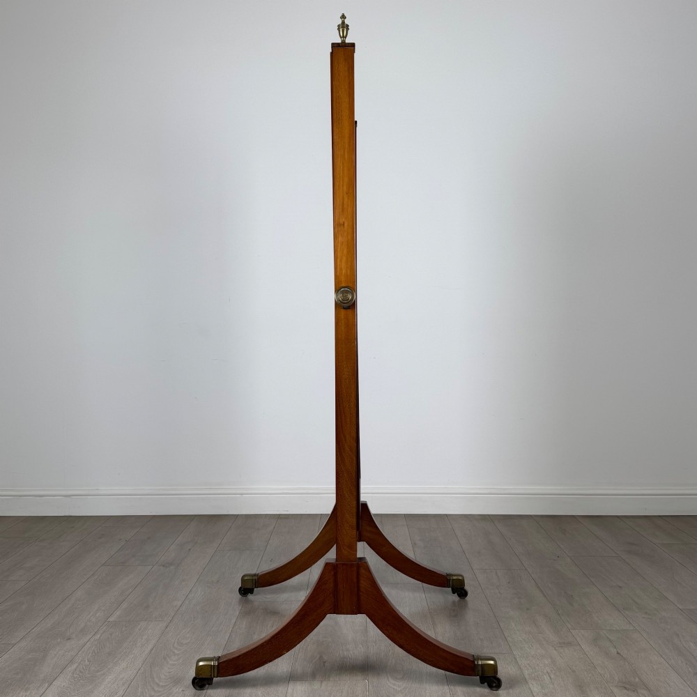 An Edwardian mahogany cheval mirror featuring a rectangular tilting mirror frame set between twin uprights with finials and splayed legs on brass castors. View II
