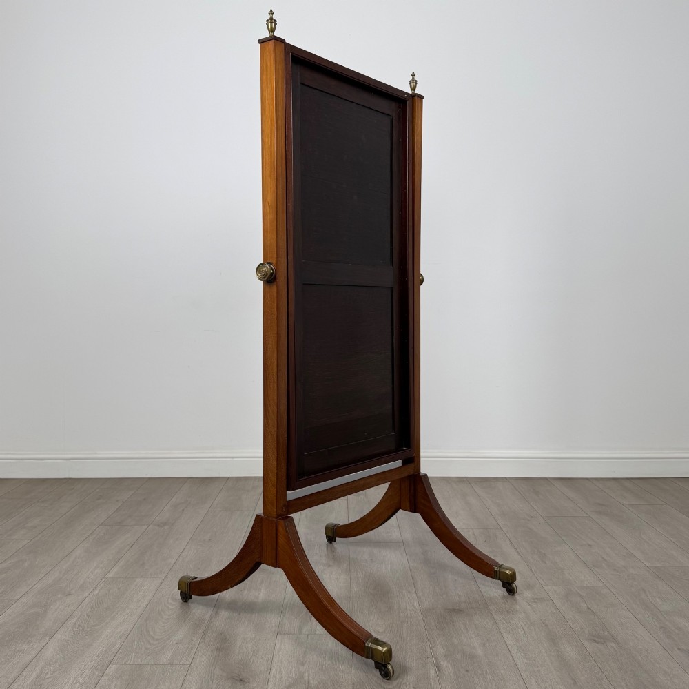 An Edwardian mahogany cheval mirror featuring a rectangular tilting mirror frame set between twin uprights with finials and splayed legs on brass castors. View IV