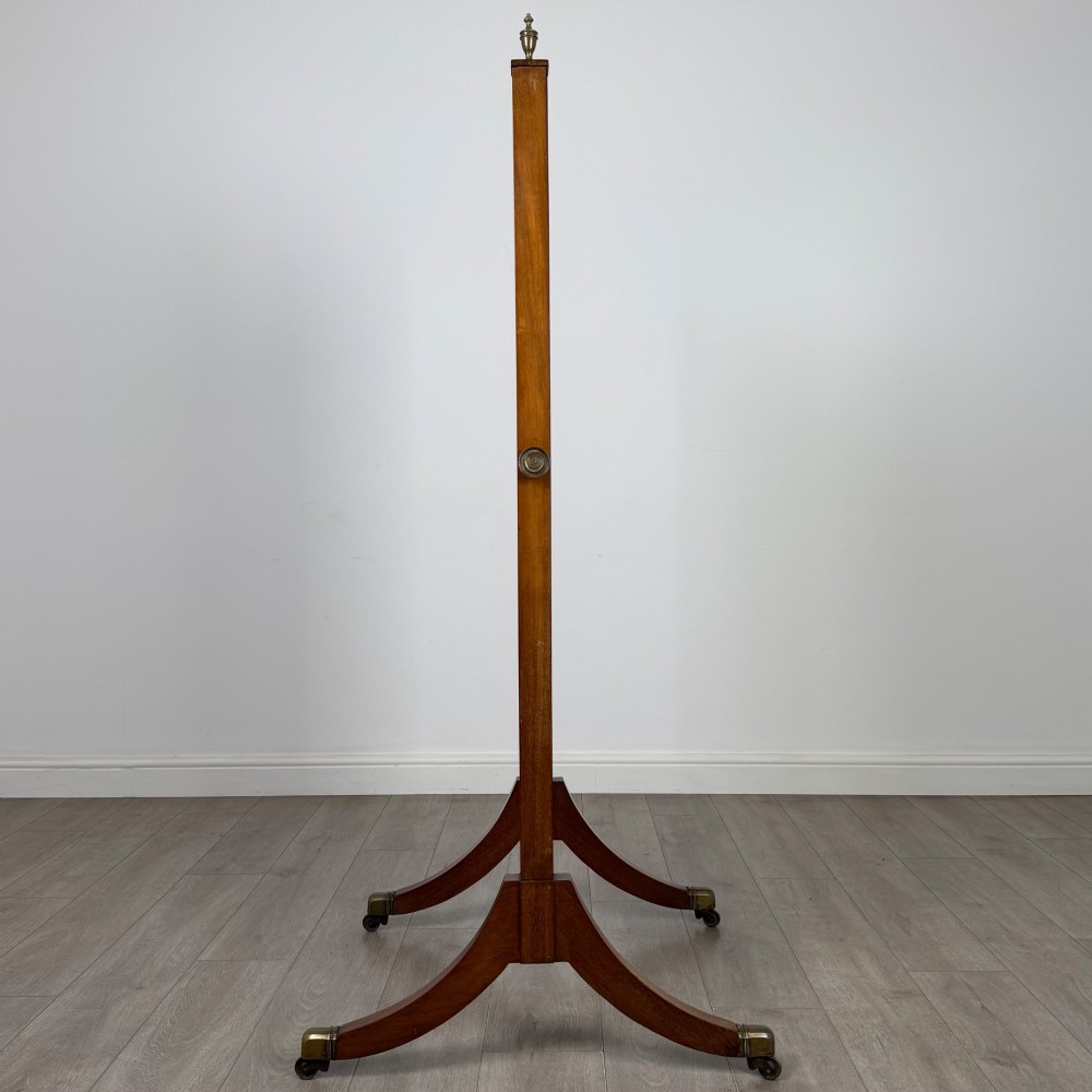 An Edwardian mahogany cheval mirror featuring a rectangular tilting mirror frame set between twin uprights with finials and splayed legs on brass castors. View VII
