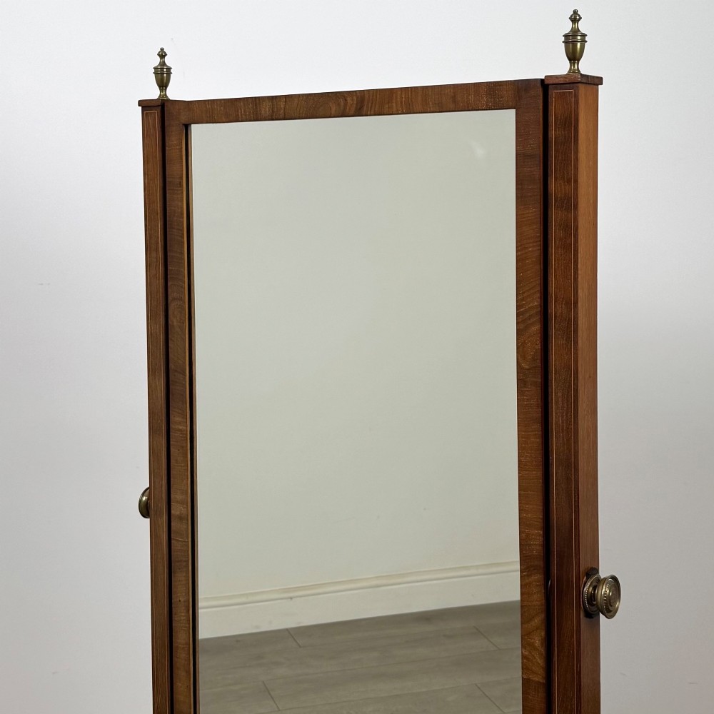 An Edwardian mahogany cheval mirror featuring a rectangular tilting mirror frame set between twin uprights with finials and splayed legs on brass castors. View XII