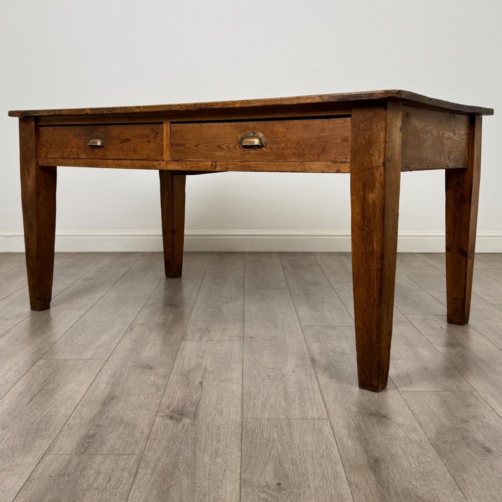 A 19th-century pine writing table featuring two front drawers with brass cup handles and tapered square legs. View II