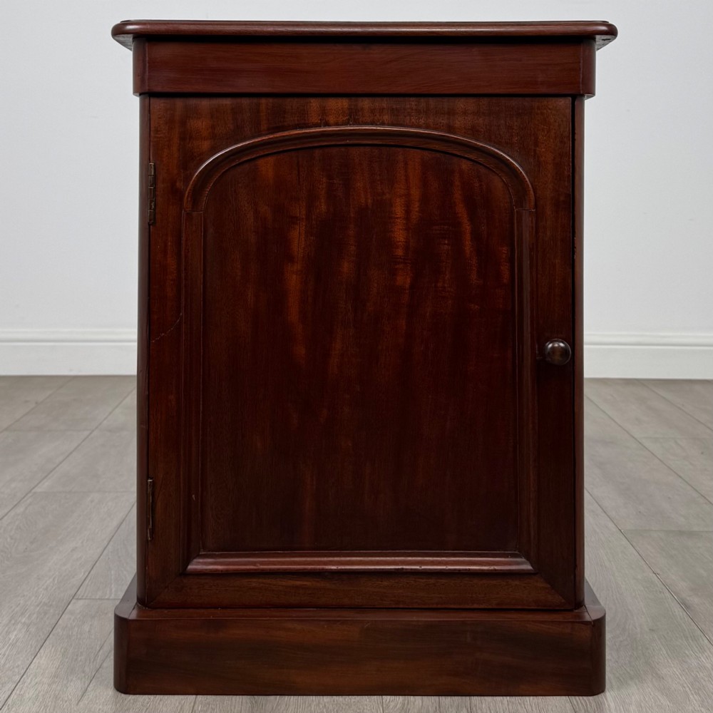 A pair of matching 19th-century Victorian mahogany bedside cabinets with single arched panel doors and plinth bases. View II