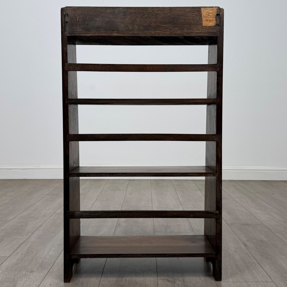 A freestanding early 20th-century warm brown open oak bookcase featuring three fixed shelves and solid side panels. View VI